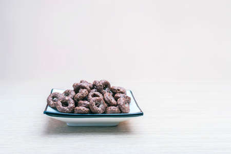 Crunchy Whole Grain Chocolate Cereals Round Oats in a Square Dish on Light Wooden Table. Healthy Organic Snack, Food, Breakfast Concept with Copy-Space.の写真素材