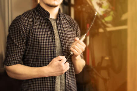 Vintage Image of a Bearded Classy Young Man in a T-Shirt and Plaid Shirt Holding Compact Bicycle...