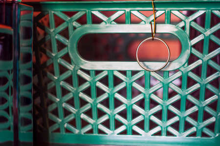 Golden Wedding Ring Hanging on a Wire Hook Attached to the Green Wardrobe Shelf Organizer Basket, With Reflections in Perfume Bottle. Breakup, Loneliness, Organizing Your Life Conceptの写真素材