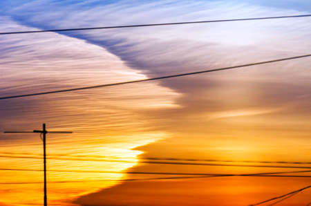 Dramatic Golden Sunset over Cityscape with Cable Wires and TV Antennas.の写真素材