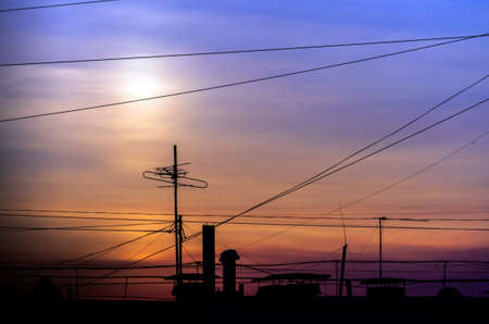 Dramatic Golden Sunset over Cityscape with Cable Wires and TV Antennas.