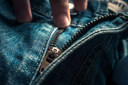 Fingers on Button and Elements of Denim Blue Jeans Metal Zipper.の写真素材