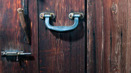 Metal Handle, Steel Latch and Wooden Bolt Hanging on a String on a Weathered Wooden Door.の写真素材