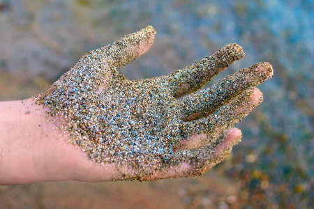 A Hand Covered with Wet Coarse Sand.の写真素材