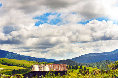 Farmhouses, Barns, Fences and Power Lines at Altai Mountains, Kazakhstan, With a Ridge in Background on a Cloudy Summer Day.の写真素材