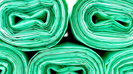 Close-up View of Rolled Green Disposable Plastic Trash Bags on White Background. Cleaning Supplies, Recycling Concept.の写真素材
