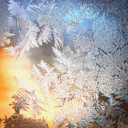 Frosty Window Glass with Natural Ice Patterns and Blurred Colorful Background. Winter Holidays Season, Fantasy World Concept.の写真素材