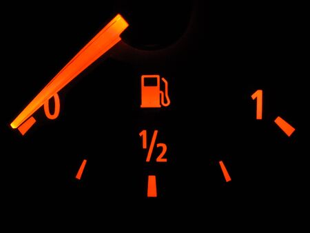 An illuminated fuel gauge showing empty  Isolated on a black background の写真素材