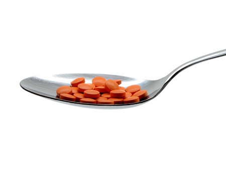 Pills in a metal spoon. Isolated on a white background.の写真素材
