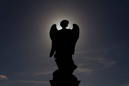 Silhouette of a statue of an angel with the sun directly behind outside Saint Angelo Castelの写真素材
