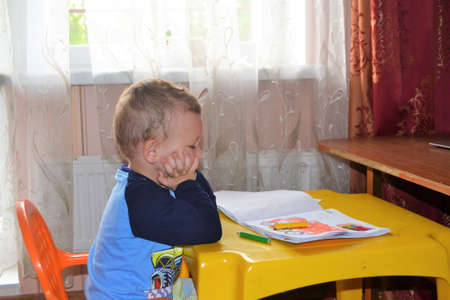 A cute little child draws a house and looks at the camera.の写真素材