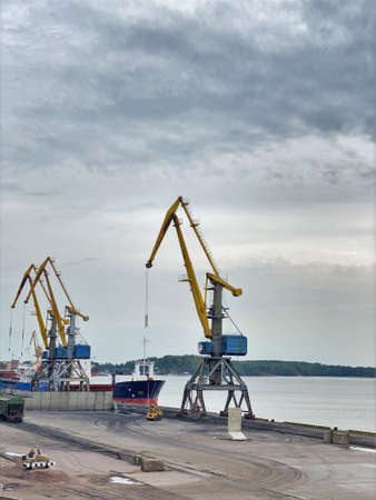 Yellow arrow of a harbor crane. Photo in the sky, equipment in the seaport. City landscape,...