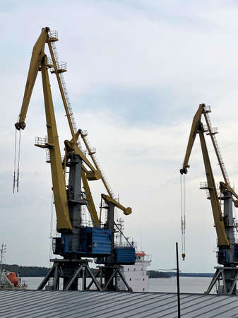 Yellow arrow of a harbor crane. Photo in the sky, equipment in the seaport. City landscape,...