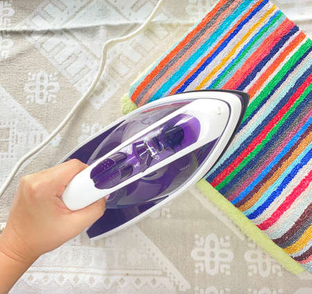 Housework, ironing colored towels on an ironing board. Close-up.の写真素材