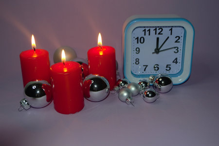 Clock and Christmas silver balls with red candles. Blurred lights in the background. New Year.の写真素材