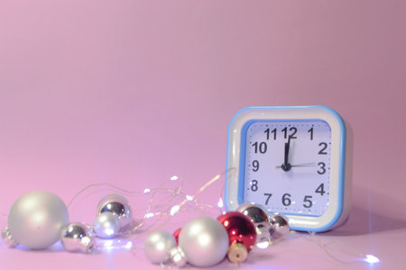 Clock and Christmas silver balls with red candles. Blurred lights in the background. New Year.