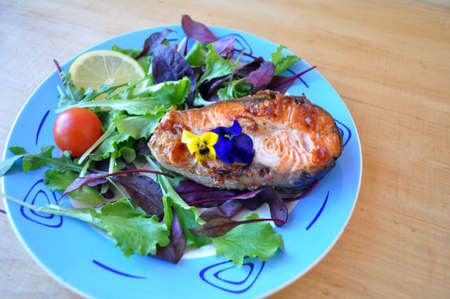 two fried fish steaks with salad, lemon, cherry tomatoes and soy sauceの写真素材