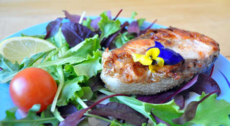 two fried fish steaks with salad, lemon, cherry tomatoes and soy sauceの写真素材