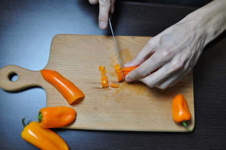 cutting vegetables, a knife in hands, on a board - tomato, cucumber, pepperの写真素材