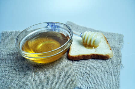 a container with honey on burlap with bread and a spoon for honeyの写真素材
