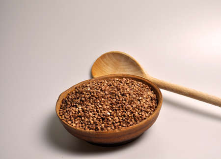 Croup for cooking porridge in a clay plate and a wooden spoonの写真素材