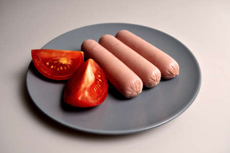 food - three sausages on a gray plate with vegetablesの写真素材