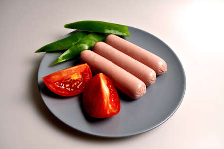 food - three sausages on a gray plate with vegetablesの写真素材