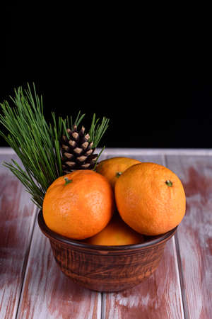 Many sweet mandarins on a table with sprigs of spruceの写真素材