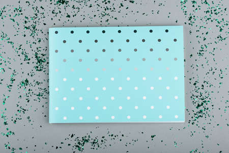 Mint color notepad on a gray background with green sparkles