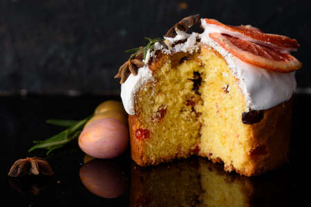 Easter cake on a dark background, decorated with rosemary and cinnamon with white icing and quail...
