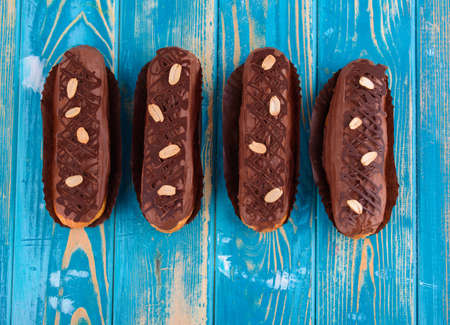 Delicious chocolate and peanut eclairs on a blue wooden table. Top view.の写真素材