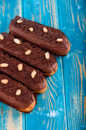 Delicious chocolate and peanut eclairs on a blue wooden table. Top view.の写真素材