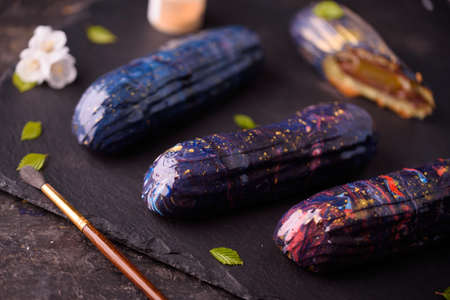 Beautiful and tasty dessert on a slate board with petals. Eclairs with a cup of coffee