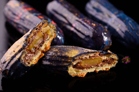 Beautiful and tasty dessert on a slate board with petals. Eclairs with a cup of coffee
