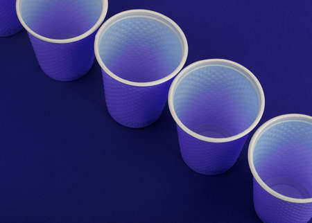 Plastic cups on a blue background. Nature's contamination with plastic.の写真素材