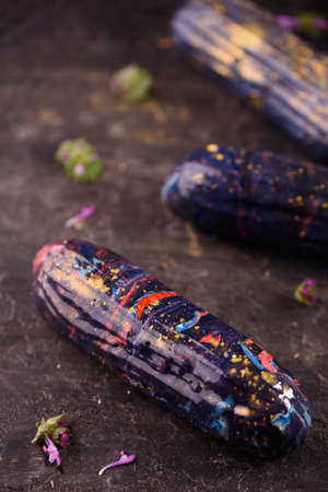 Beautiful and tasty dessert on a slate board with petals. Eclairs with delicious cream