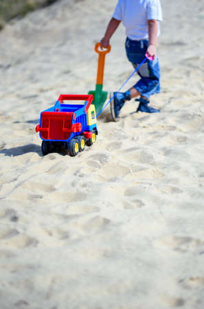 Boy on the beach with a toy car in the sandの写真素材