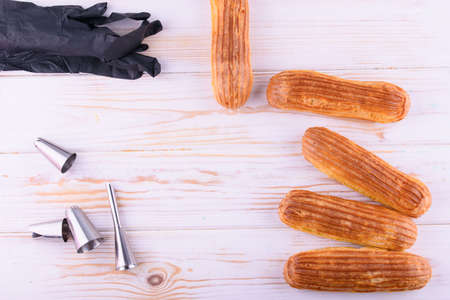 Tasty and beautiful eclairs with chocolate on a wooden board. Appetizing dessert. Party supplies