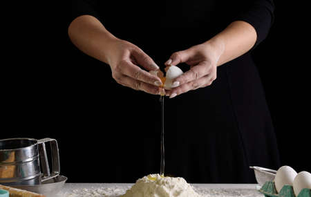 Chef hands on a black background, in the process of cookingの写真素材