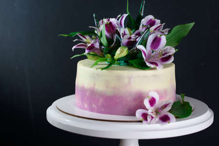 Delicious, beautiful, festive cake with fresh flowers on the tableの写真素材