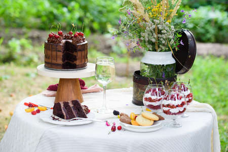 Delicious chocolate cake, red velvet in a glass, wild flowers, berries. Summer picnic outside the city.の写真素材