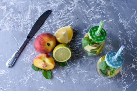 Cooling drink with fresh fruit and ice on a concrete background. Peppermint, peach, lemon, lime.の写真素材