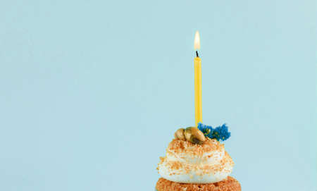 Beautiful festive cupcake on a light green background with sparkles and a single candle. Partyの写真素材