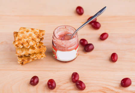 Tasty and aromatic honey in a jar with dogwood berries on a wooden table. View from aboveの写真素材