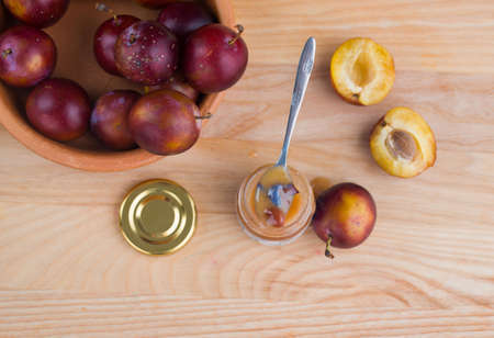 Tasty and aromatic honey in a jar with plums on a wooden table. View from aboveの写真素材