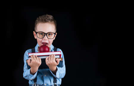 Cheerful smiling little boy on a black background. Looking at camera. School concept. Place for text