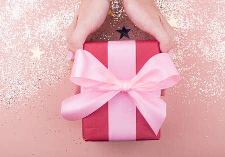 gift box with woman hand on a beautiful background with a satin ribbon. Holiday conceptの写真素材