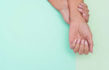 Stylish trendy female manicure. Beautiful young woman's hands on green background.の写真素材