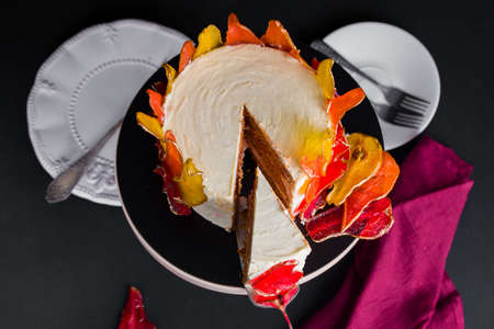 Beautiful and delicious dessert. The cake on the stand is decorated with red and yellow pears on the black backgroundの写真素材