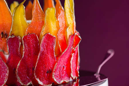 Beautiful and delicious dessert. The cake on the stand is decorated with red and yellow pears on the black backgroundの写真素材